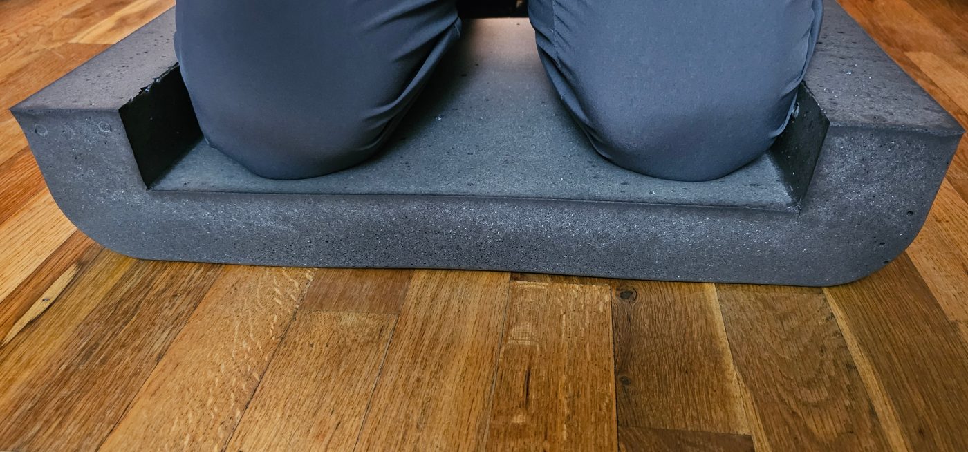 Person kneeling in the cradle of a charcoal ProteKnee foam kneeling pad on a wood floor